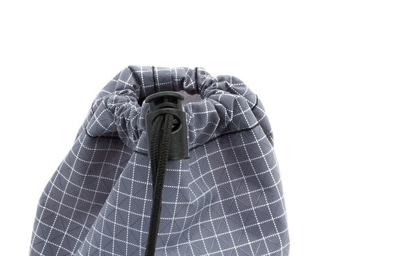 A close shot of a Size 1 Northwest Sky (light grey with white grid) 200 Halcyon Travel Stuff Sack with it's drawstring cinched shut and held in place using the thumb-operated locking piece.